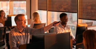 Office with employees at computer workstations, roller shades along the sunlit windows