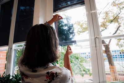 Woman pulling down a roller shade at the window