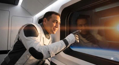 Astronaut in a spacecraft pointing through the window at the sun above the Earth